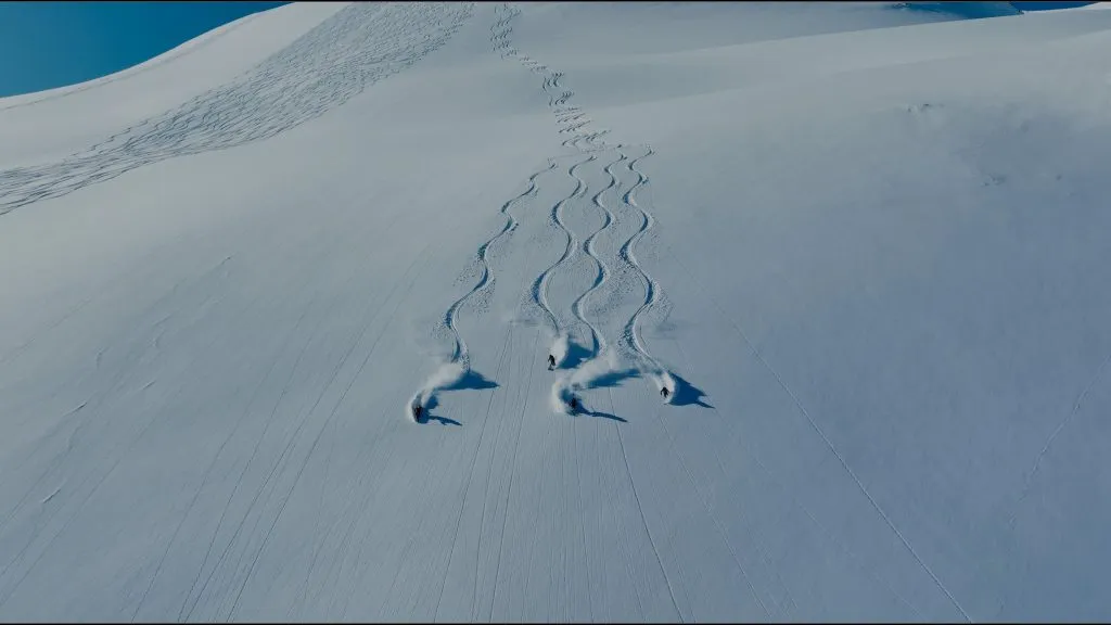 skiers carving snow on slope