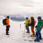 skiers overlooking snowy mountains